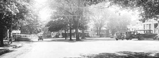 Signs on the left side of the intersection in the 1920s and ’30s point out 110 and 111, with Ayer, Littleton, Lowell and Amesbury on the left; Boxborough, West Acton, Concord and Boston on the right.  Blur on the left is a moving car. (Photo courtesy of Harvard Historical Society)