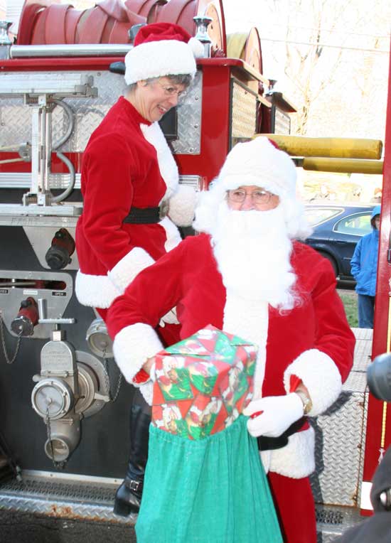 Santa and Mrs. Claus disembark from a firetruck as they arrive at the Congregational Church.