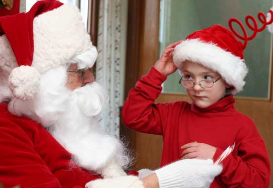 Santa offers Lucas Conant a candy cane.