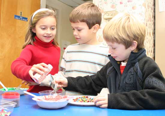 Kaeli Armstrong, Jack Armstrong, and Mitch Sampson decorate holiday cookies in the kids corner at a youth group fundraiser held at St. Theresa’s.