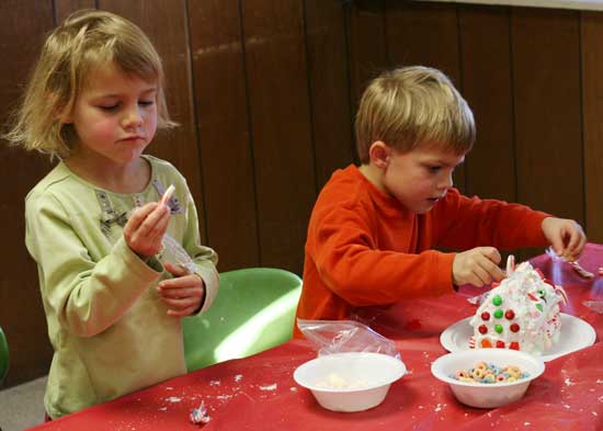 Twins Kaia (left) and Caeden Bishop work on a graham cracker house at the Congregational Church's Christmas Fair.