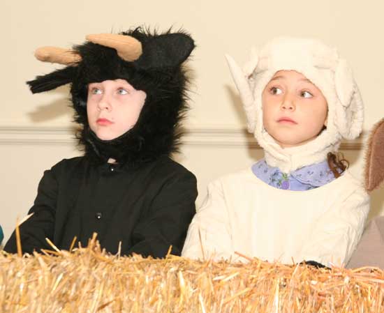Jamie Aciukewicz and Pilar Vellante watch attentively as they pose as manger animals.