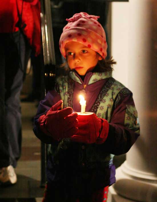 Five-year-old Isabelle Barton holds a candle in front of the Unitarian Church on her way to the annual tree lighting festivities on the Common.