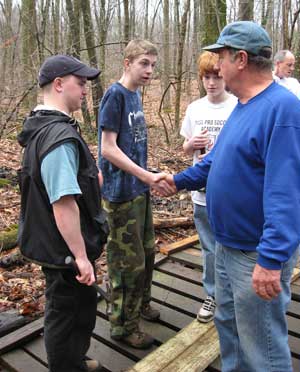 Nick Ostertag accepts a handshake from Paul Willard (right) for his work in completing the bridge as Tom Cooke (left) and Evan Cochrane (second from right) look on. (Photo by Laura Andrews) Nick Ostertag accepts a handshake from Paul Willard (right) for his work in completing the bridge as Tom Cooke (left) and Evan Cochrane (second from right) look on. (Photo by Laura Andrews)