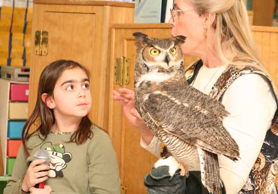 Second-grader Maya Grant listens as Marcia Wilson of Eyes on Owls, an educational program on owls, calls to her Great Horned Owl.
