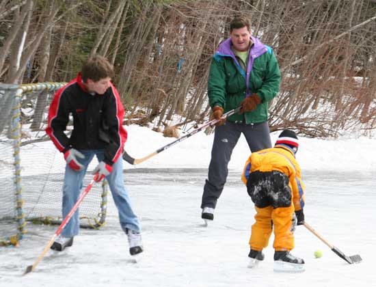 Hunter, Jeff, and Nolan Granville play hockey at the town reservoir.