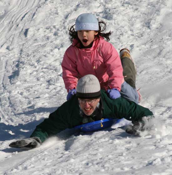 Proving it's not just for kids, David Kassel picks up speed with daughter Emma on his back as they sled on the hill behind the high school.