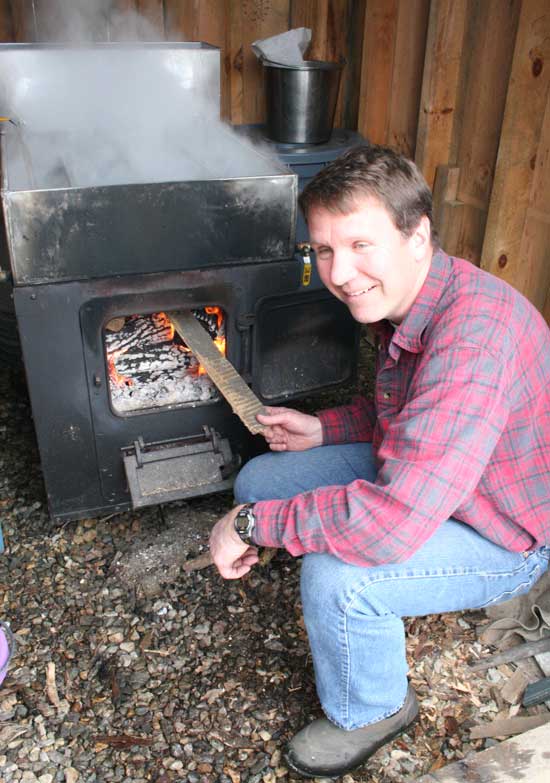 Karl Nocka feeds the fire under his evaporating pan. Karl Nocka feeds the fire under his evaporating pan.