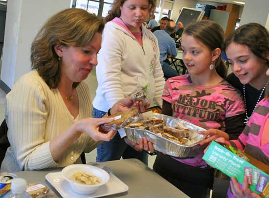 Fifth-graders Bella Romatelli, Jackie Planchet,and Heather Graham sell baked goods to Laura Martineau at Town Meeting lunch.