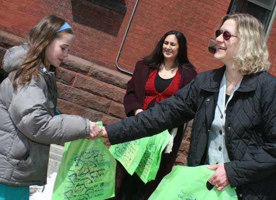 Jane Sullebarger (left) gets a book to carry in the parade from children’s librarian Abby Kingsbury as Nicole Blankenshop looks on