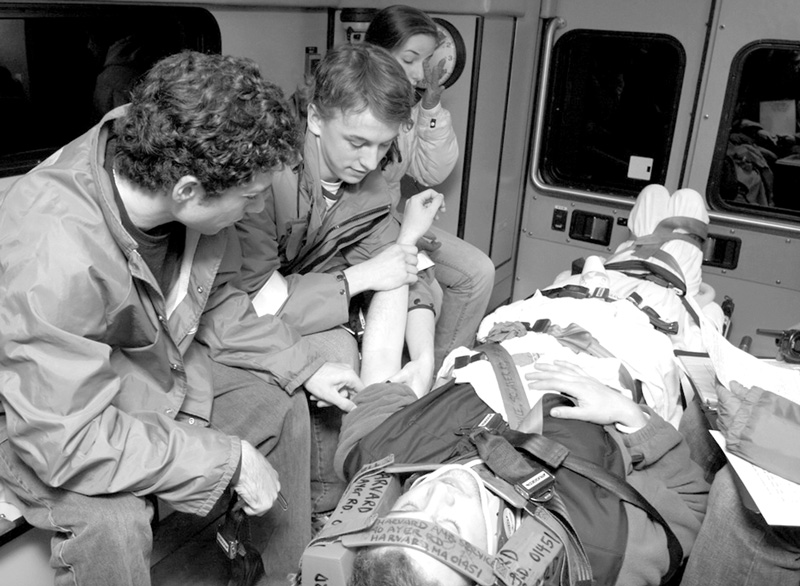 EMTs-in-training Nick Parker, Harry Powell, Katie Papazian transport a fellow student in the ambulance during a training drill. (Photo by Rob Williams)