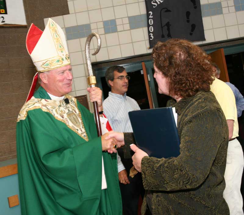 Bishop of the Diocese of Worcester Robert McManus shakes hands with Judy Romatelli after a service in the Cronin Auditorium. (Photo by Lisa Aciukewicz)