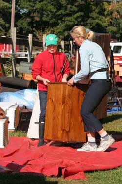 Deborah Skauen-Hinchliffe and Carol Kapolka carry an antique dresser out of the Historical Society to dry on the lawn.