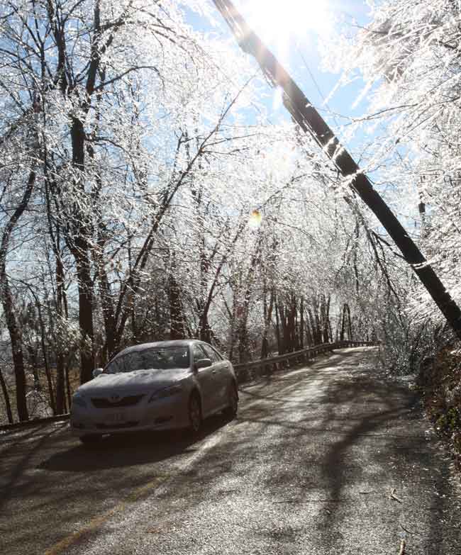 A car drives under one of many damaged telephone poles in town, this one on Stow Road.