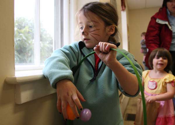 Autumn Femino collects eggs at at the Harvard Family Association Egg Hunt as Julia Riddle trails behind.