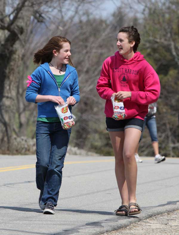 Haley Newsham and Laura Jarvis, eighth-graders at Bromfield, enjoy some jelly beans while walking on Prospect Hill during the Good Friday Walk last Friday to benefit Loaves & Fishes.