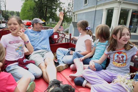 From left: Scarlett O’Brien, Eric O’Brien, Penelope Schnier, Noah Blaker, and Gwyneth Evans ride down Mass Ave. atop a firetruck during the festivities at the Apple Blossom Festival.