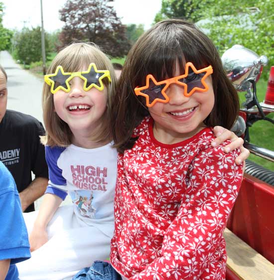 Nina Green and Emily Douglas are star-struck as they ride down Slough Road on a fire truck.