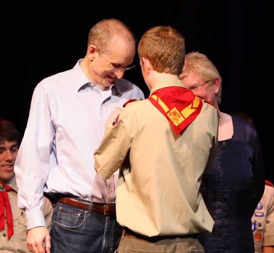 Chris Gunner (left) receives a pin from his son, Eagle Scout Will Gunner, as his mother, Bess Haire, looks on.