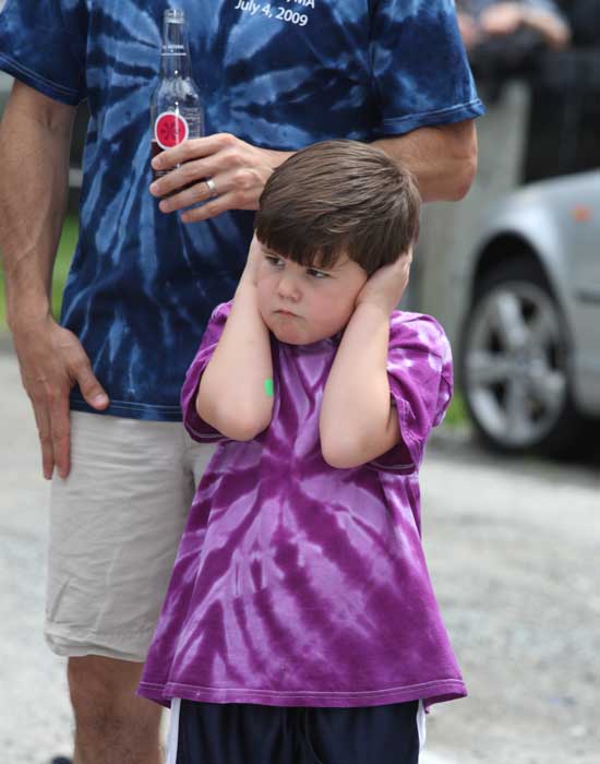 Logan Anderson covers his ears as the emergency vehicles sound their sirens. 
