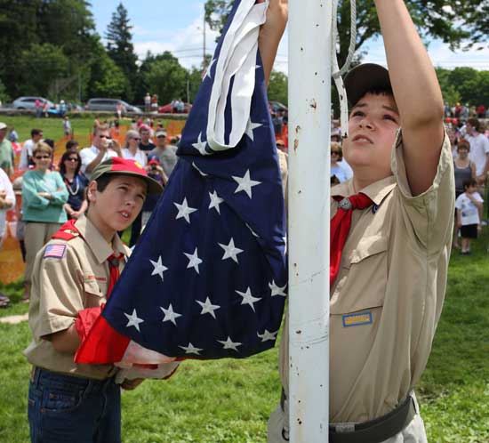 Boy Scouts Peter Donaldson (left) and Brendan Beale raise the flag in front of Old Bromfield at the start of the July 4th ceremonies.