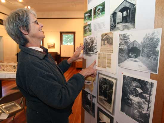 Judy Warner hangs photographs at the Harvard Historical Society for the upcoming show, "Covered Bridges of New England."
