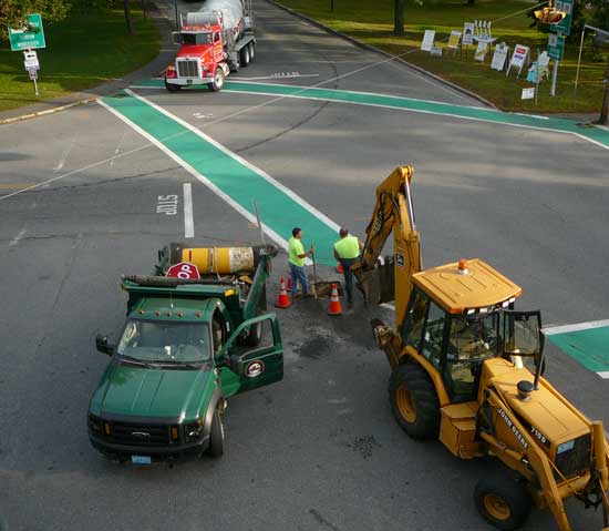 A Department of Public Works crew removes the much-maligned concrete foundation from a stop sign at the intersection of Ayer and Still River Roads in the town center. (Photo by Worth Robbins)