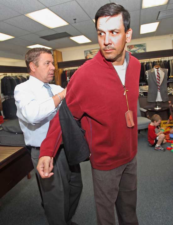 Joe Cabral of Gould's clothing store helps Harvard firefighter Bill Barton try on an outfit for the "Fall Into Fashion"show held the following night, Sept. 24, at Fruitlands Museum. The event was a benefit for the Council on Aging.