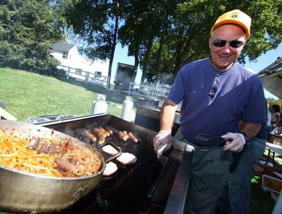 Lions Club member Mark Boudreau grills up sausages with peppers along with burgers and hot dogs. 