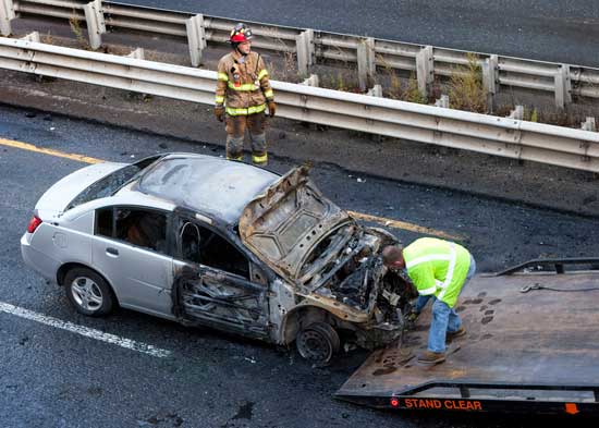 A vehicle is hooked onto a tow truck after a two-car collision stopped traffic in its tracks on Route 2 near the intersection with Routes 110/111 on September 28. No one was seriously injured despite the fact that both vehicles burst into flames. (Photo by Ellen Harasimowicz)