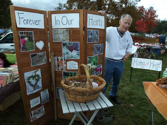 Jim Schautz, the late Jessie Peterson's grandfather, mans a booth at the annual Columbus Day Weekend Flea Market, encouraging residents to create a heart-shaped object in memory of Jessie. Jessie was fatally injured in March when a tree fell in the family's yard.