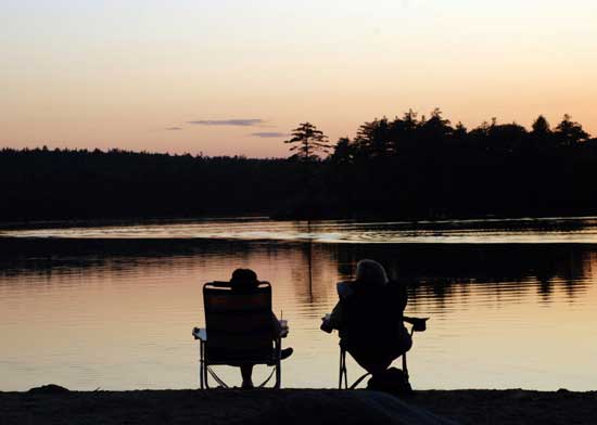 A pair relaxes and watches the sun set over Bare Hill Pond. (Photo by Sue Fitterman)