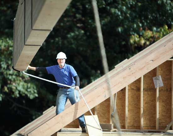 Construction Supervisor Bill DiBurro guides a 52-foot-long, 4,700-pound beam suspended by a crane into place during construction of a new Fellowship Building for the Unitarian Universalist Church on Elm Street.