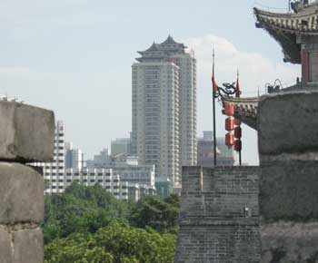 Some Chinese buildings are a mixture of old and new, as is this small skyscraper topped by a pagoda as seen in the background of some older buildings (Photo by Ben Myers)