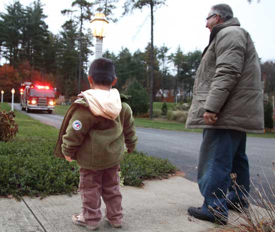 Charlie Eiland watches with his father, Bob Eiland, as  a firetruck pulls up his street to pick him up for school.