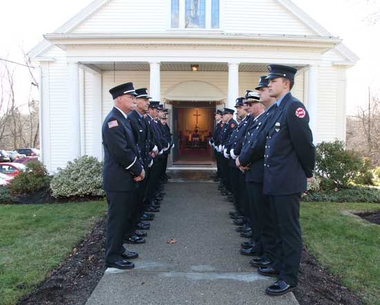 Firefighters from Harvard and surrounding towns line the walkway in front of  Harvard’s Holy Trinity Parish at the funeral of PJ Johnston, a 45-year veteran on the force, on Dec. 2.