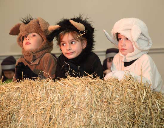 Manger animals Ethan Taylor, Sarah Sobalvarro, and Tori Ferguson listen to the choir at the annual Ecumenical Christmas Pageant.