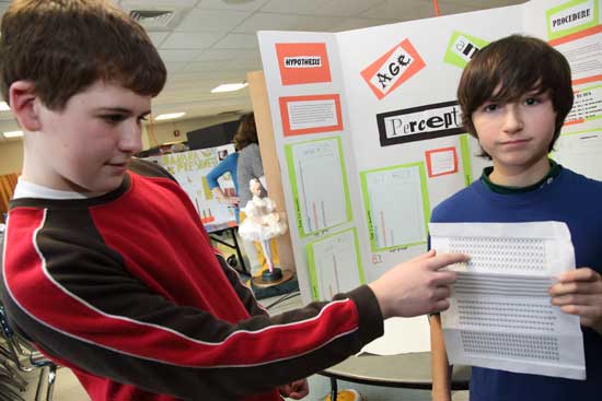 Sixth-graders Ryan Byrne (left) and Thos Brown display the sheet they used in their experiment on age and perception in which participants of various ages identified a unique item in a group.