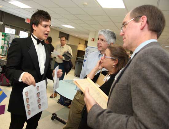Dapper 12th-grader Clark Jacobson tells judges Doug Rothkopf, Holly Rothkopf, and Stephen Friedrich about his experiment, The Effect of Beauty on Job Applications.
