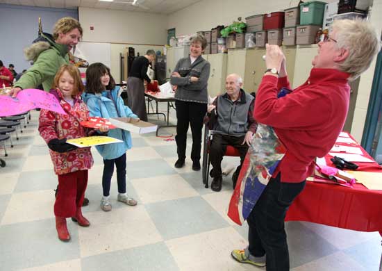 From left: Jen Schoenberg, Shea Oldham, and Samantha Schoenberg pose as Michelle Girard and her father, Richard Wheeler, watch For Art's Sake's Bess Haire take a photo of the girls and their finished Valentines.