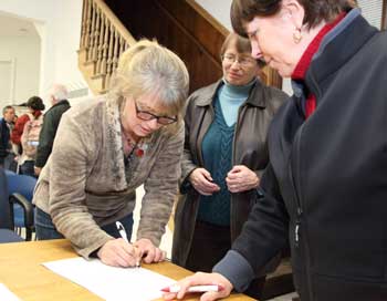 From left: Kirsten Wright signs her nomination papers for a seat on the School Committee as Marty Green and Rhonda Sprague look on at the Town Caucus on March 6. (Photo by Lisa Aciukewicz