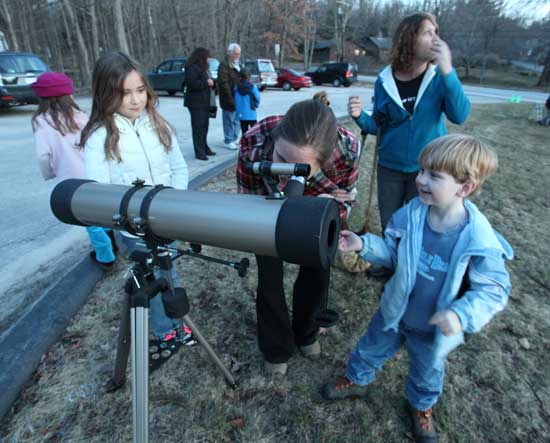 Madison Drummey, Beth Drummey, Kim Houston, and Logan Houston gather around one of the many telescopes.