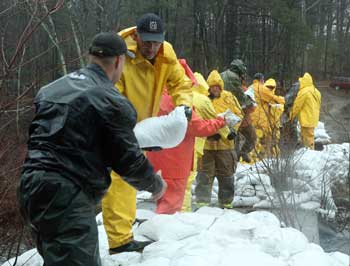 Members of the Department of Public Works and the Fire Department form a bucket brigade as they pass sandbags to shore up the dam on Bare Hill Pond on March 30 after more rain fell during the wettest March on record. (Photo by Lisa Aciukewicz) Members of the Department of Public Works and the Fire Department form a bucket brigade as they pass sandbags to shore up the dam on Bare Hill Pond on March 30 after more rain fell during the wettest March on record. (Photo by Lisa Aciukewicz)