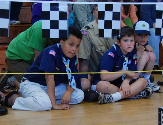 Grant Oliver (left) and Connor O'Shea look on intently as the cars fly to the finish at the Cub Scouts' Pinewood Derby on April 11.  (Photo by Laura Zupancic)