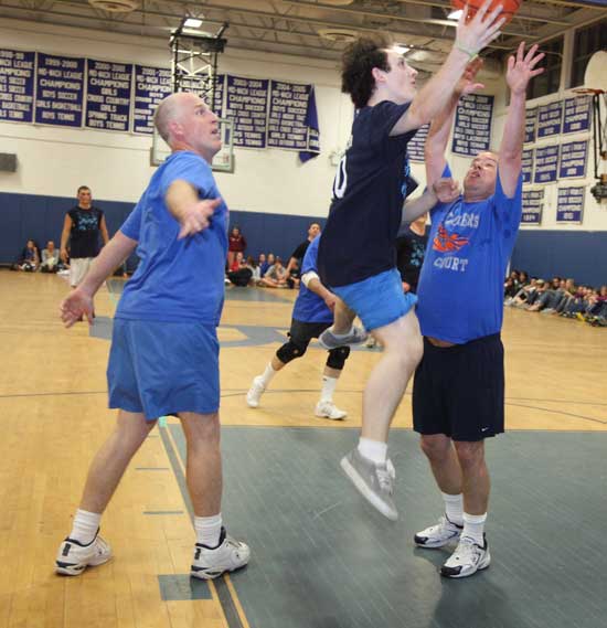 Tyler Lahanas (center) flies through the air as Principal Jim O’Shea (left) and Vice Principal Scott Hoffman try unsuccessfully to block his drive.
