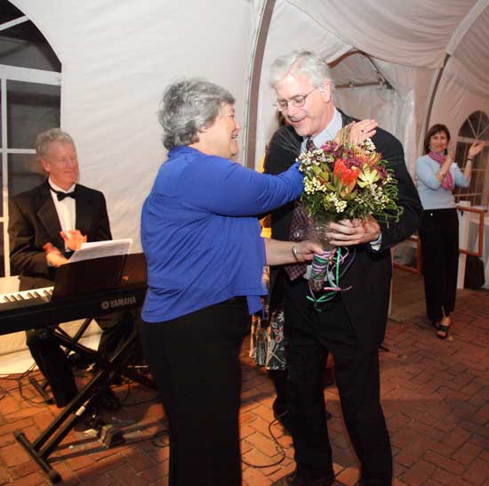 Retiring teacher and drama director Michael McGarty receives a hug and a bouquet of flowers from Schools Trust board member Weezie Potter, as well as a standing ovation from the crowd in recognition of his 34 years at Bromfield.