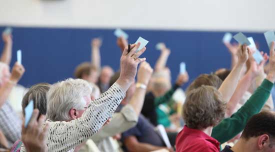 Hands are raised for one of several unanimous votes.