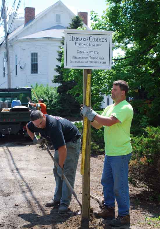 Eric Martineau (left) and Jeff Greco of the Department of Public Works install a sign near Town Hall on May 6 to mark the boundary of the Town Common Historic District.