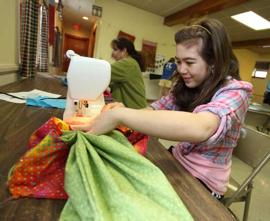 Amy Hunter sews a border on a pillowcase at the April 23 Girl Scout "Sew-In" to make pillowcases for sick children.