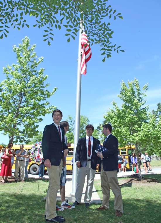 Scott Broadbent, Jack Landry, Jake Basile, and Garrett Kistler stand under a just-raised flag that was sent to Bromfield in thanks for collecting and sending supplies to troops in Camp Leatherneck in Afghanistan.